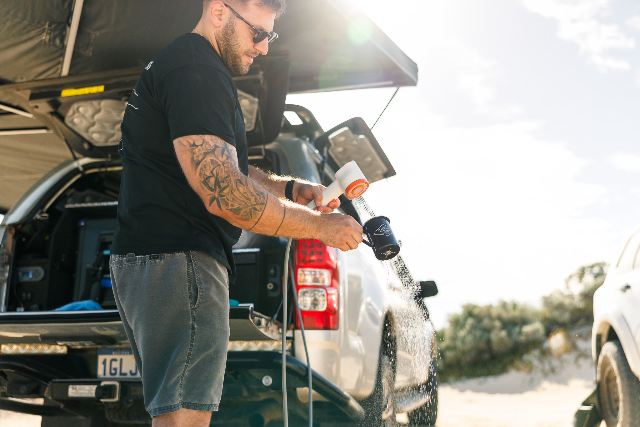 Camper using a Niche Outdoors water bladder with a camp shower setup